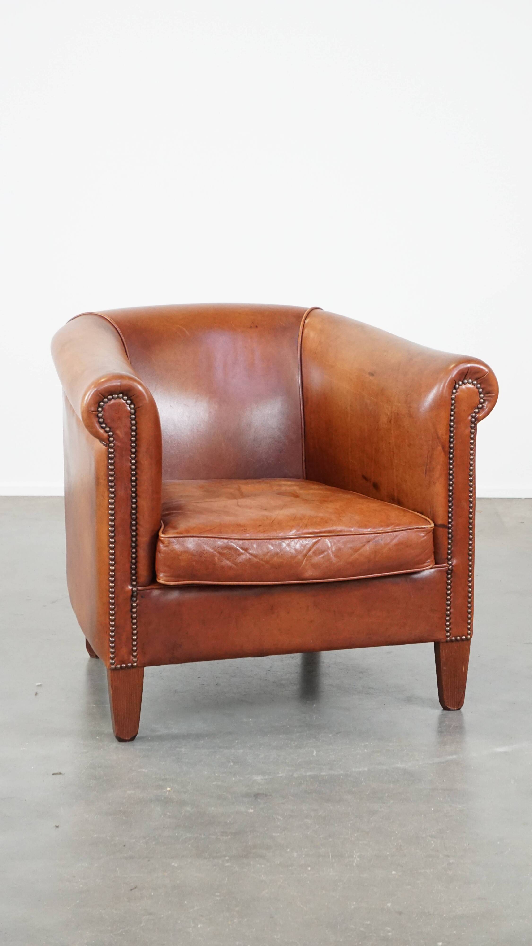 Cognac-colored cow leather club chair finished with decorative nails in English style