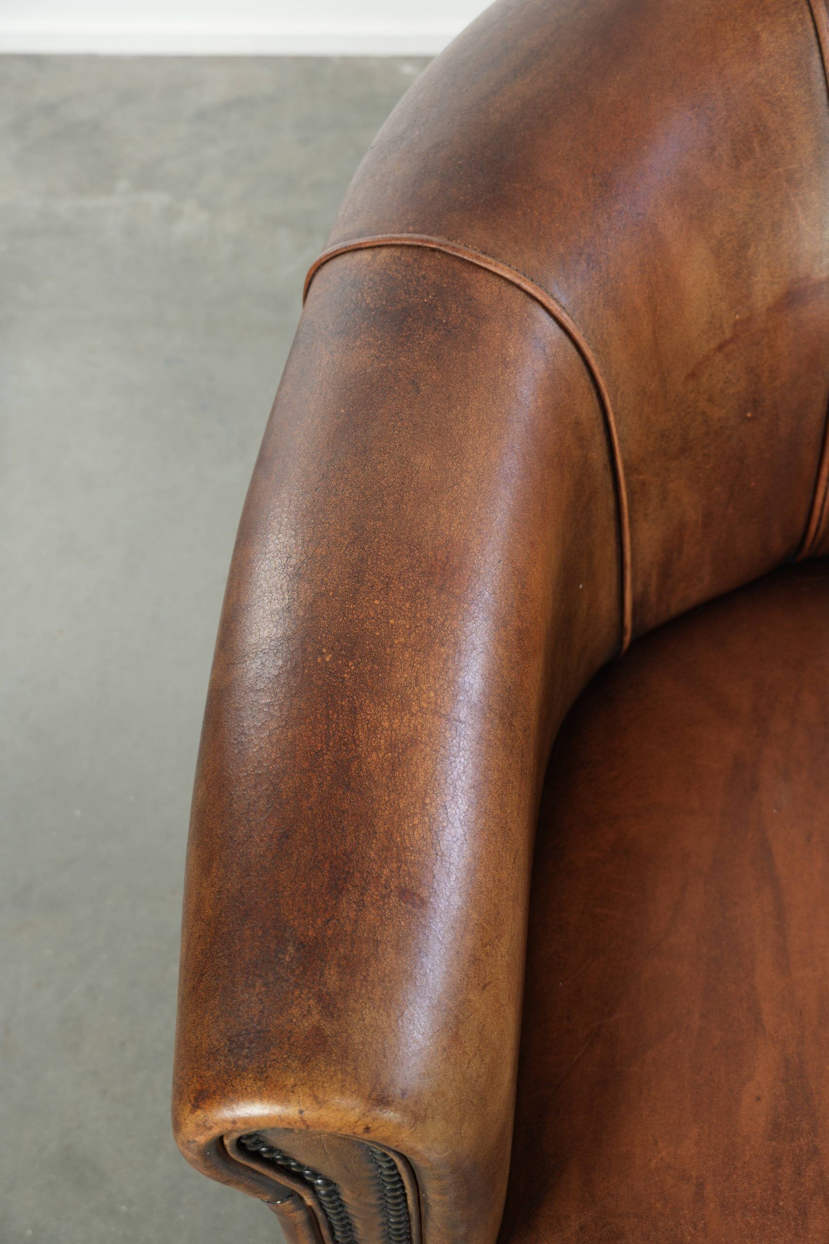 Sheepskin clubarmchair with beautiful patina finished with decorative nails