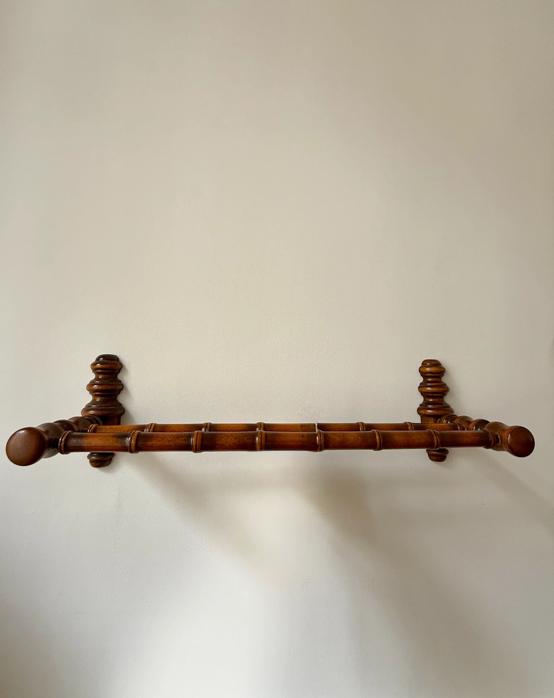 Wall-mounted coat rack made of turned wood in a bamboo style.