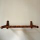 Wall-mounted coat rack made of turned wood in a bamboo style.