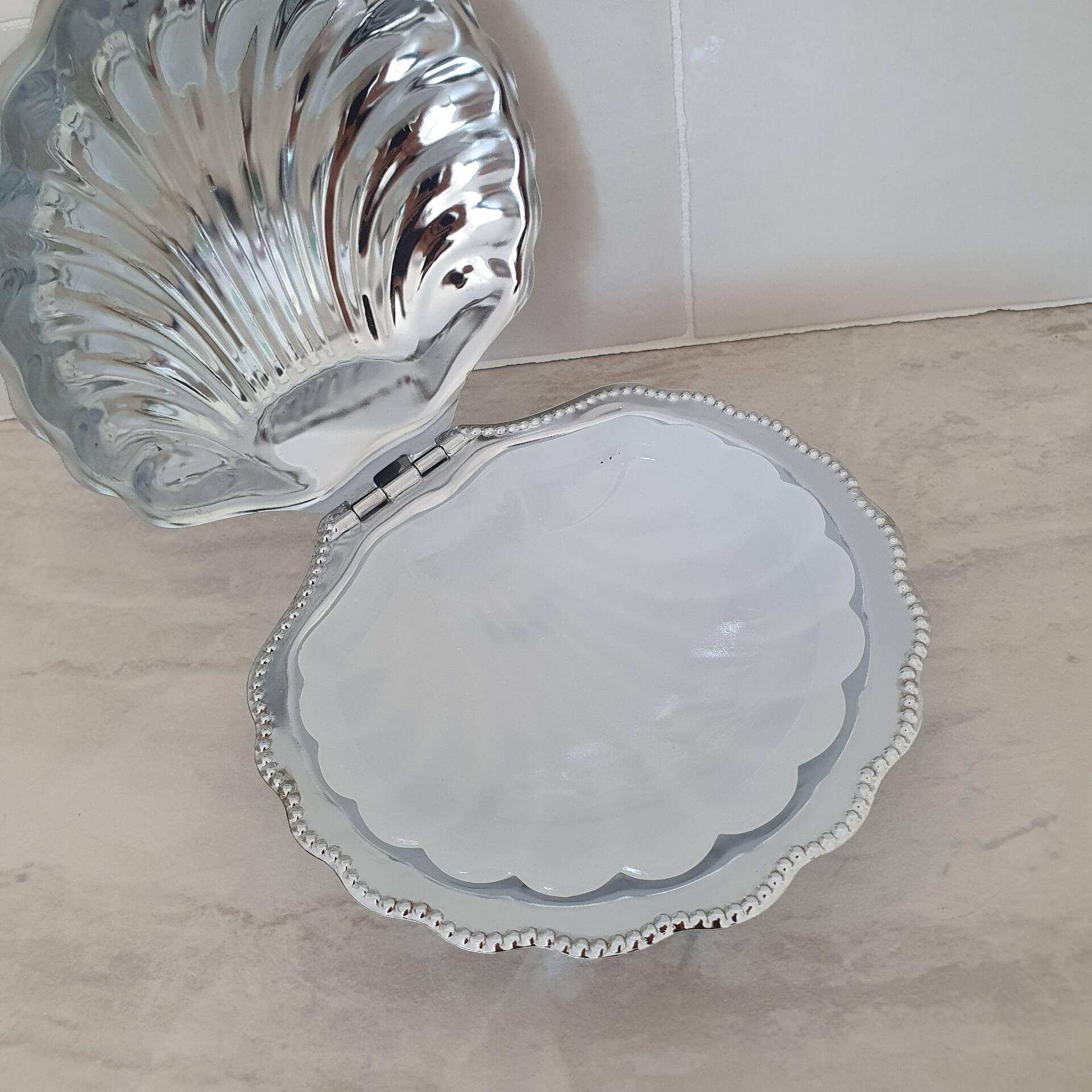 Scallop shell butter dish in stainless steel with its white glass saucer.