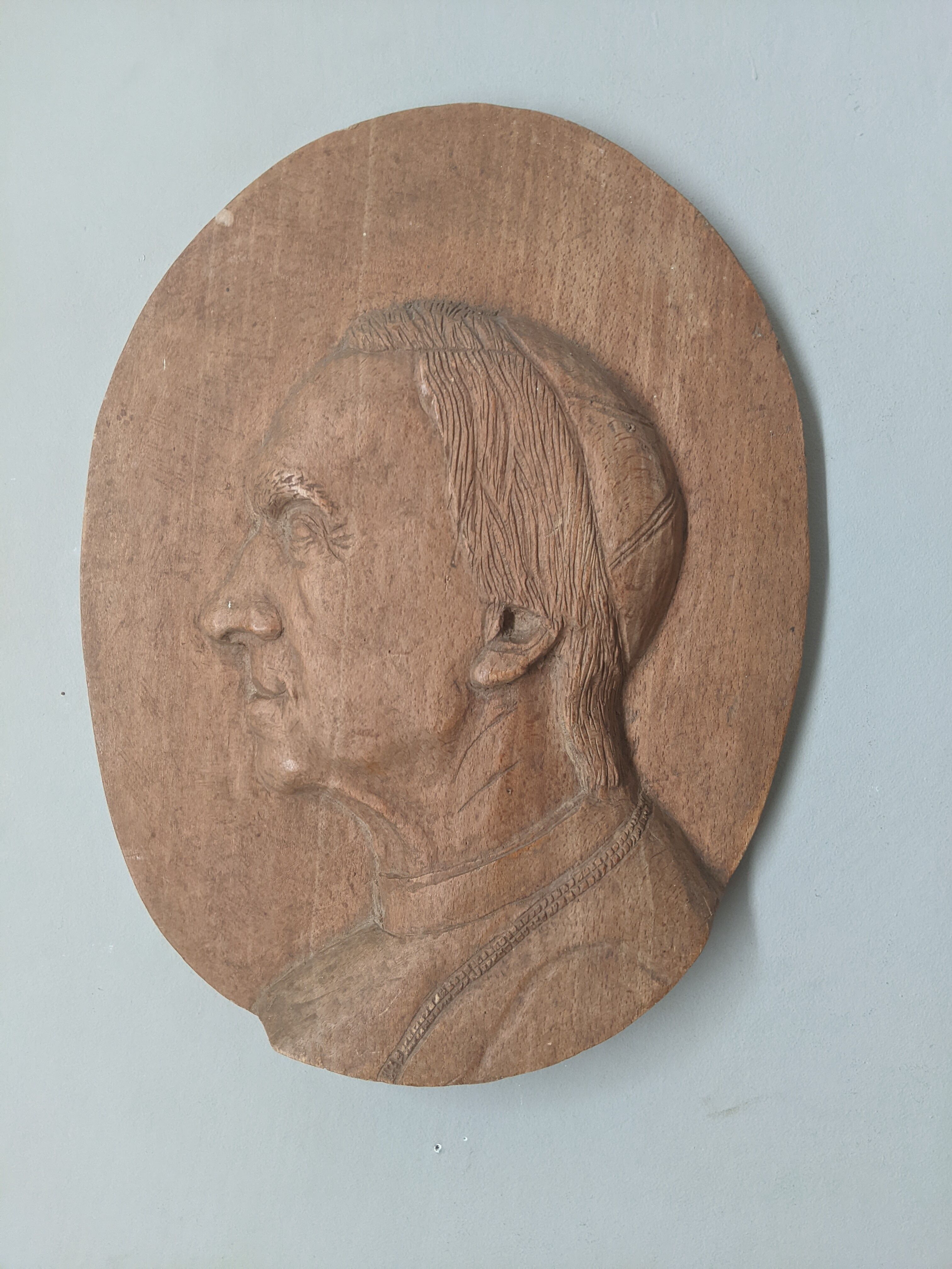 Oval wooden relief portrait of a cardinal.