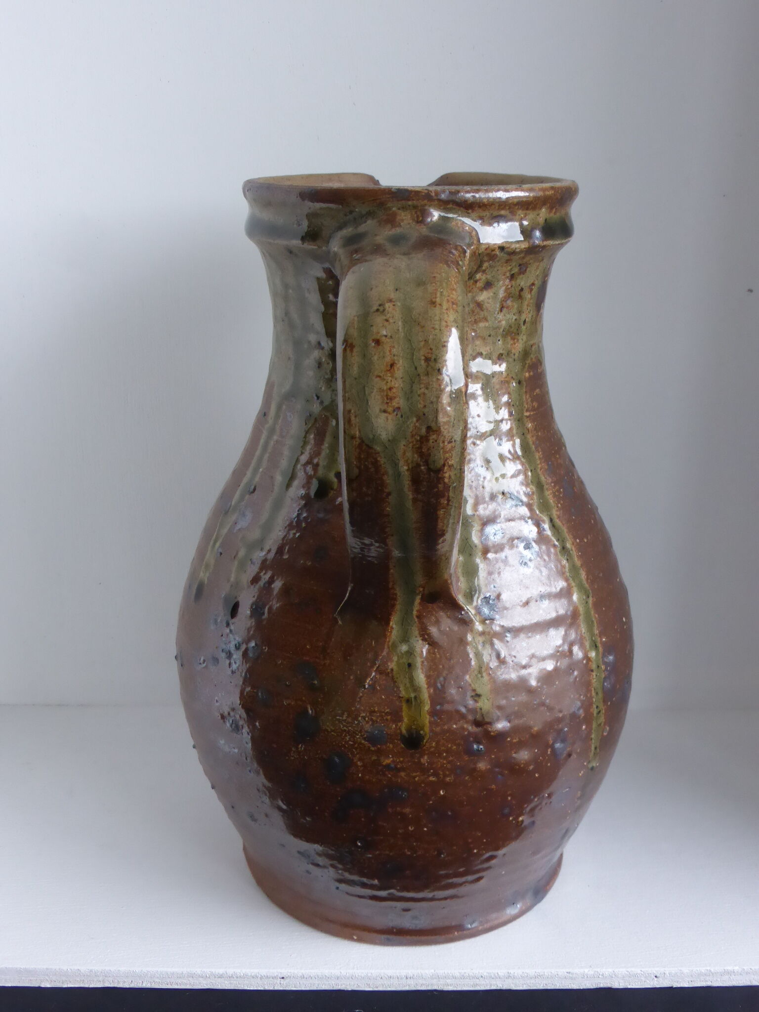 Old pitcher in brown sandstone with green drippings
