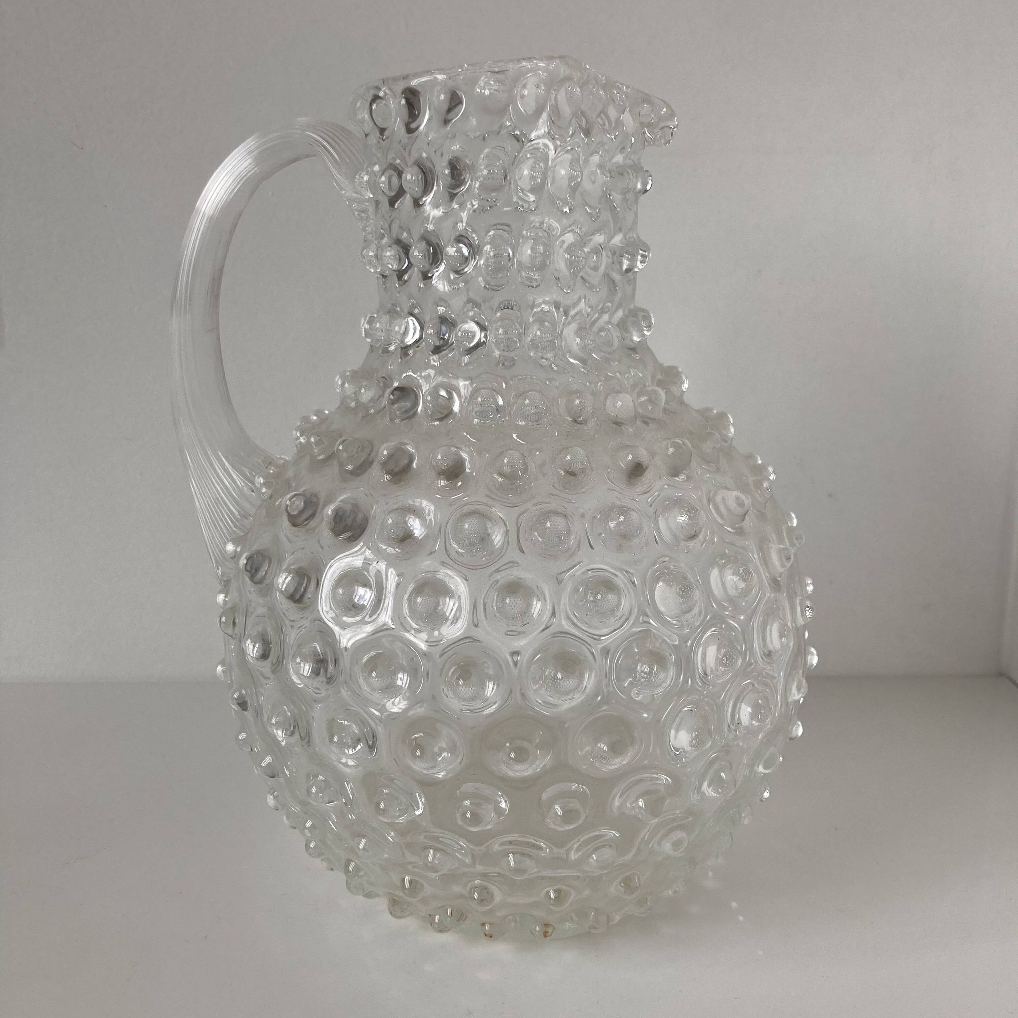 Beautiful and large vintage glass jug with a handle, made of clear hot-worked glass.