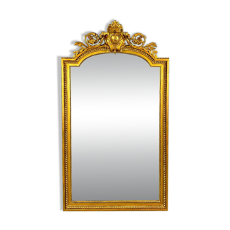 Large antique gilded wooden mirror in Louis XVI style with a sculpted pediment, 19th century.