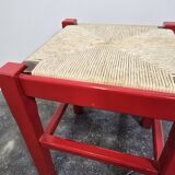 Red wooden stool with woven rush seat.