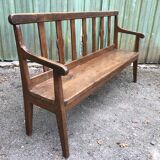Duo of old solid oak benches with backs and armrests.
