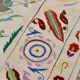White suzani kilim rug with embroidered multi-colored patterns
