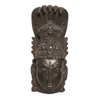 Ancient Indian carved wooden mask sculpture of a deity with a cobra.