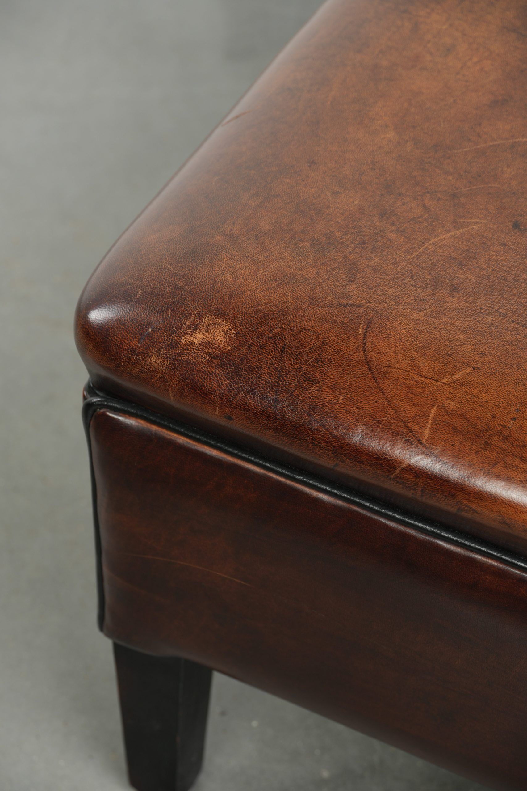 Large dark brown square ottoman made of sheepskin with black piping