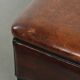Large dark brown square ottoman made of sheepskin with black piping