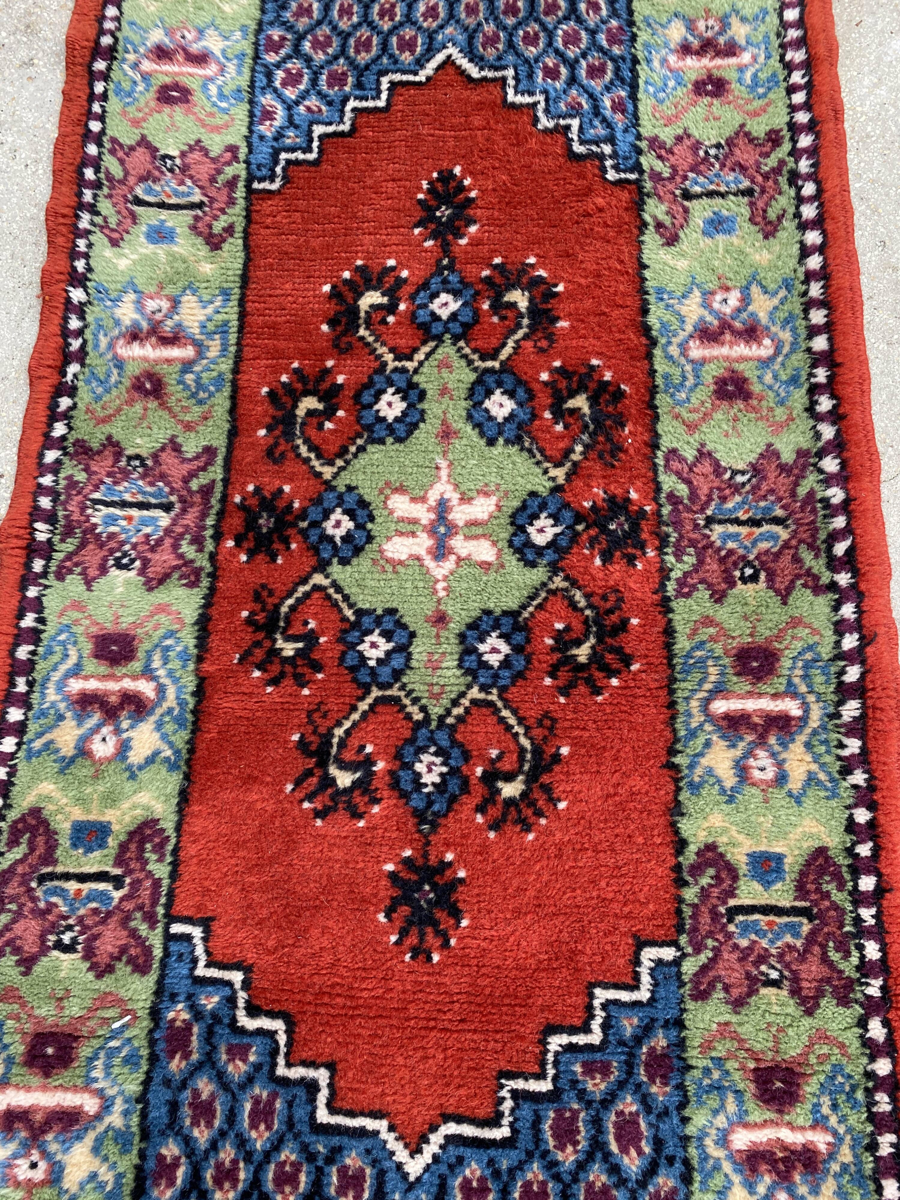 Vintage hand-knotted wool rug with polychrome decoration on a red, blue, green background 150 x 63 cm