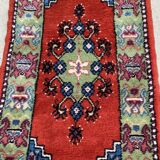Vintage hand-knotted wool rug with polychrome decoration on a red, blue, green background 150 x 63 cm