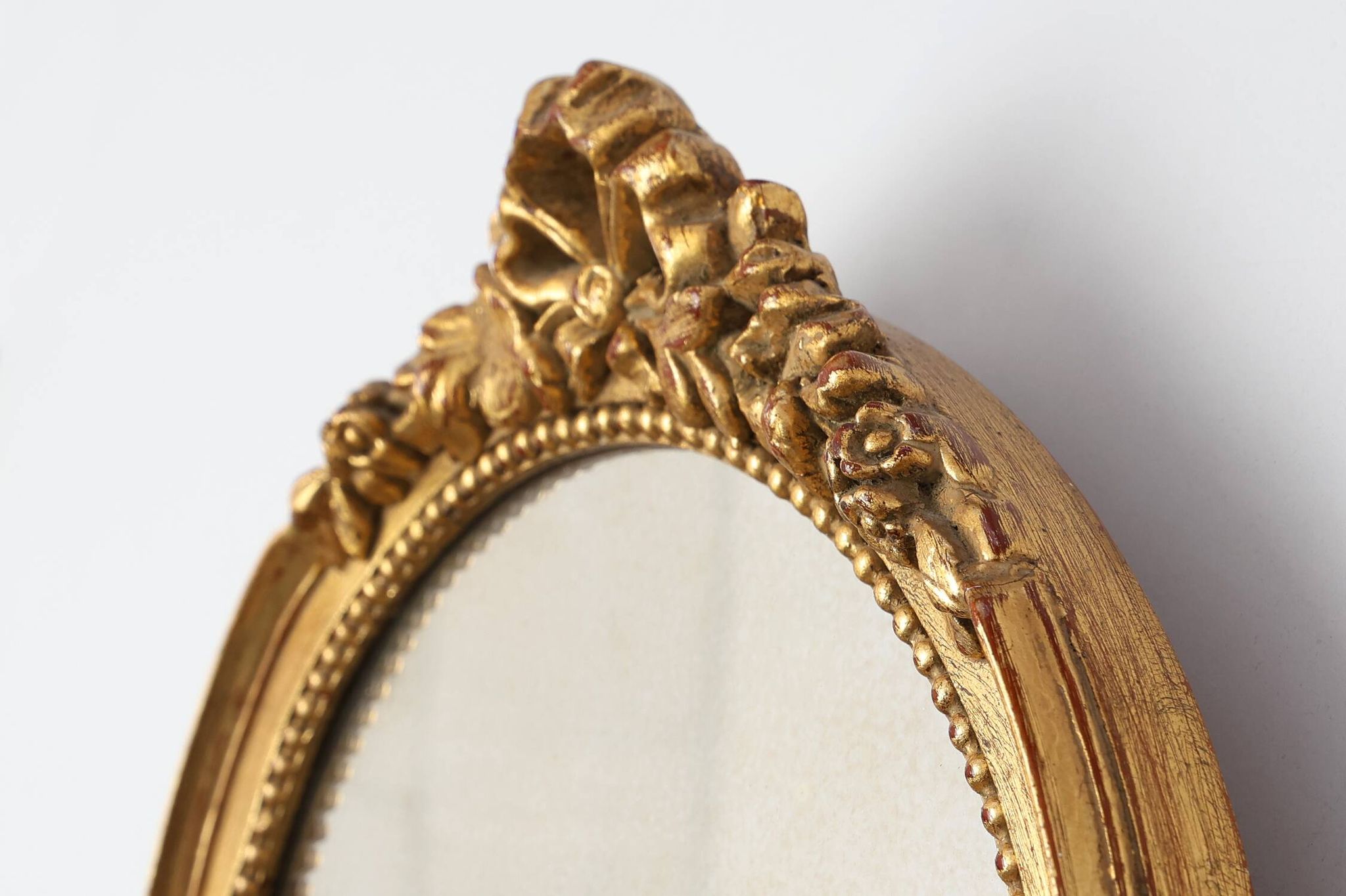 Oval giltwood mirror with rococo-style floral crest, mid-20th century