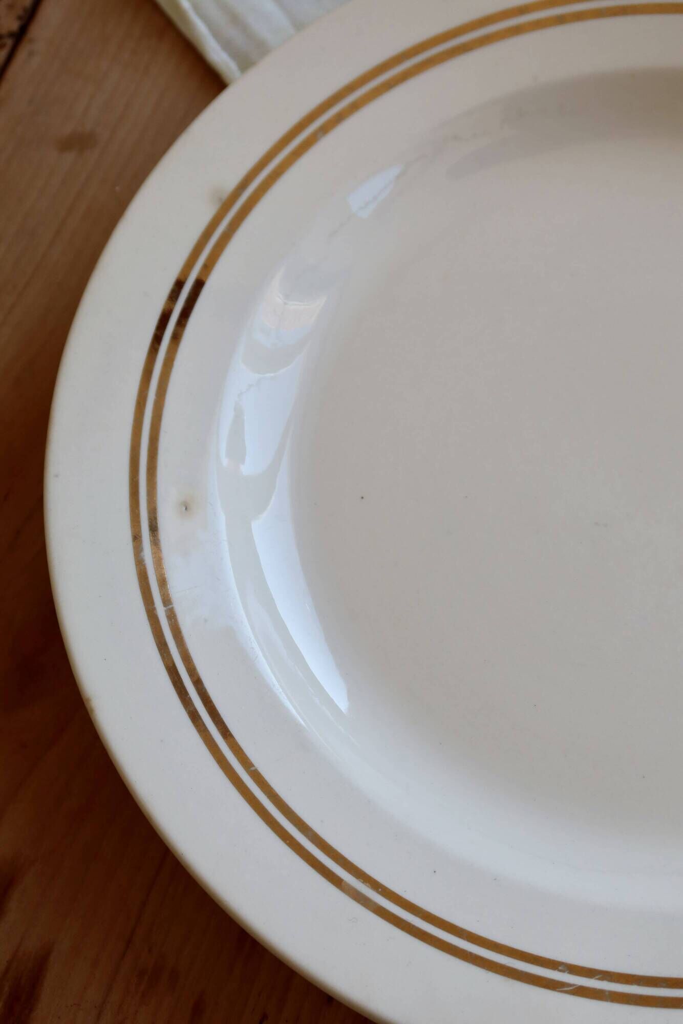 Round vintage ivory earthenware serving dish with double gold trim.