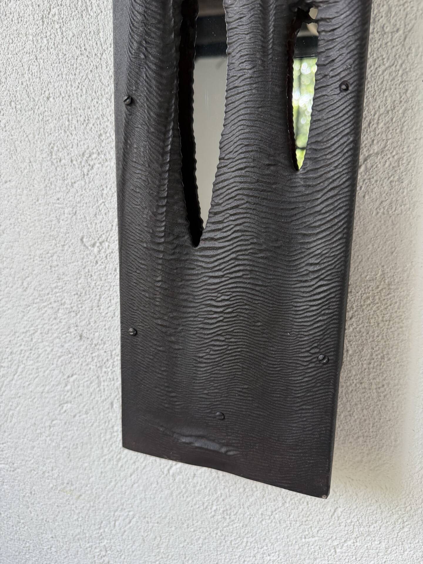 Brutalist hammered mirror, free-form, patinated metal.
