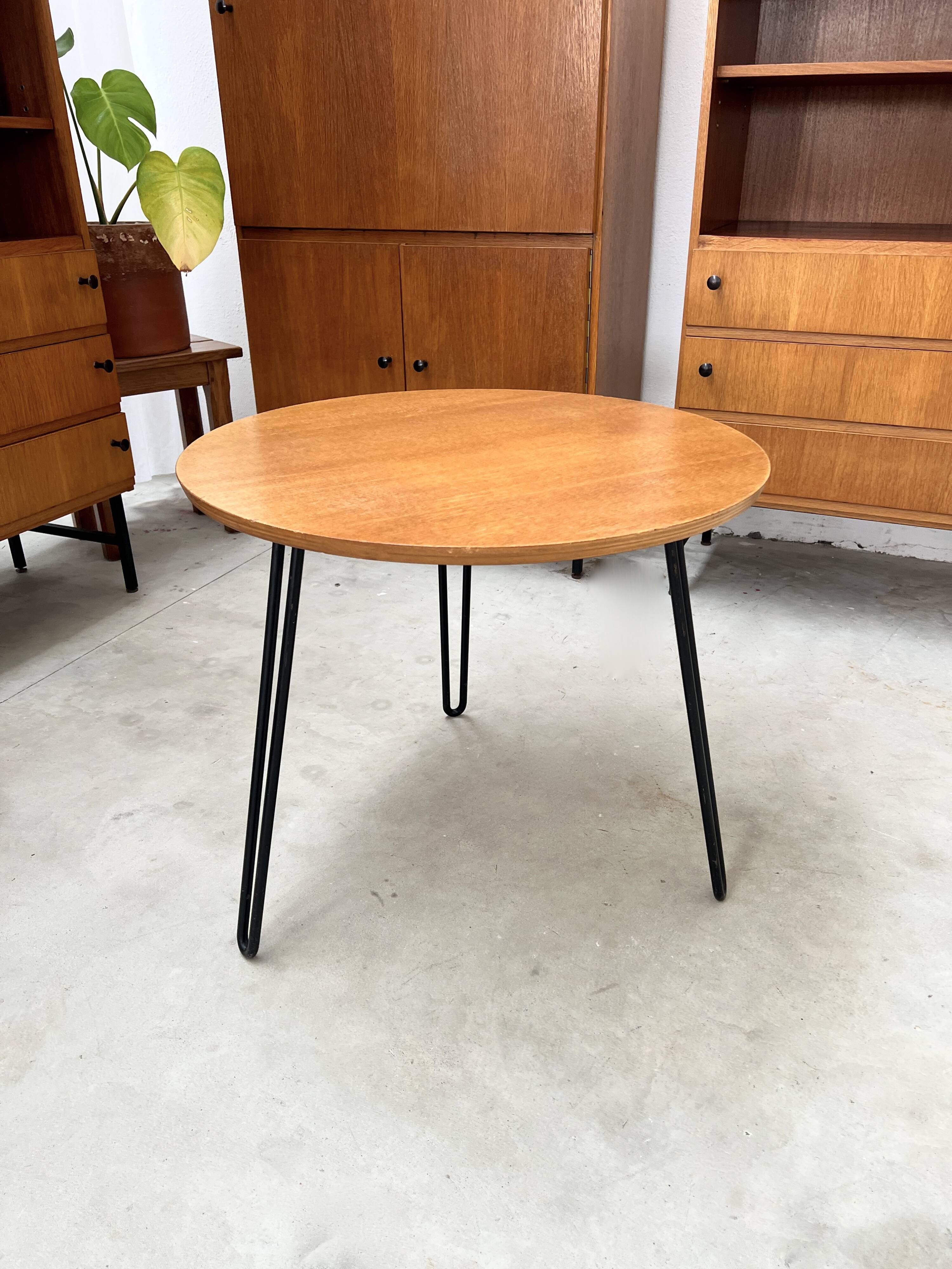 Round side table with black lacquered metal hairpin legs.