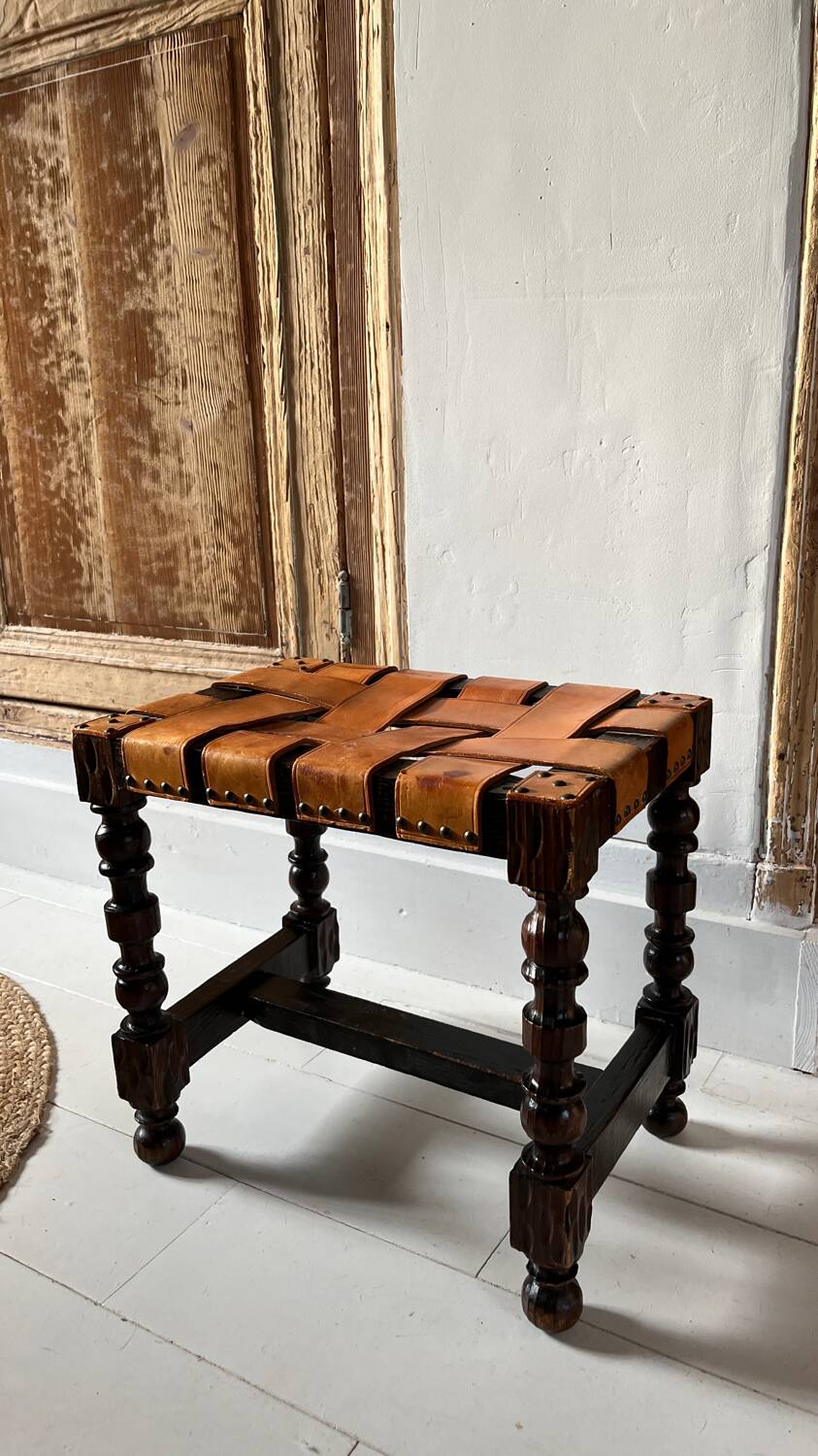 Antique turned wooden stool with woven leather.