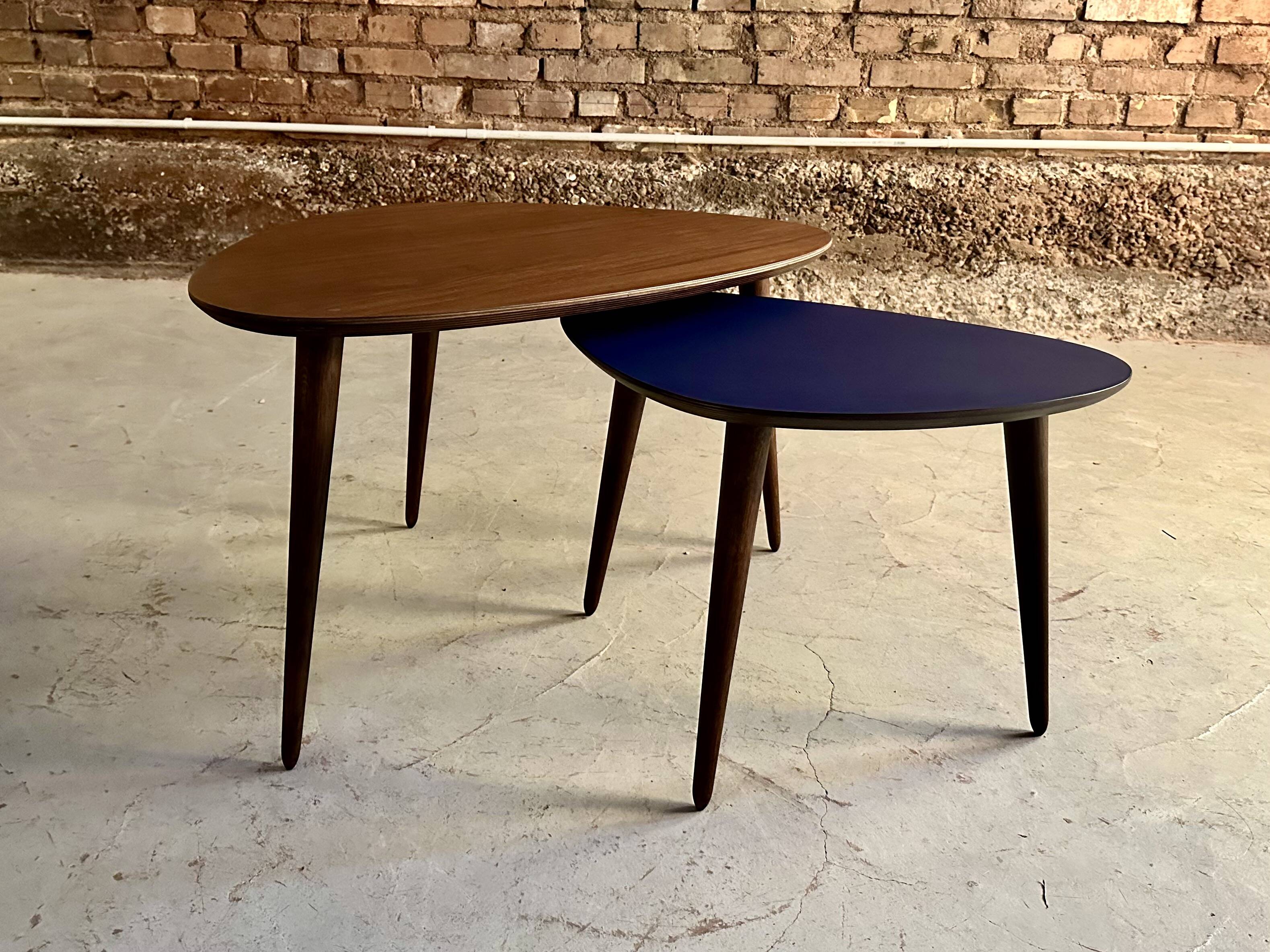 A pair of tripod and nesting coffee tables in walnut and midnight blue.