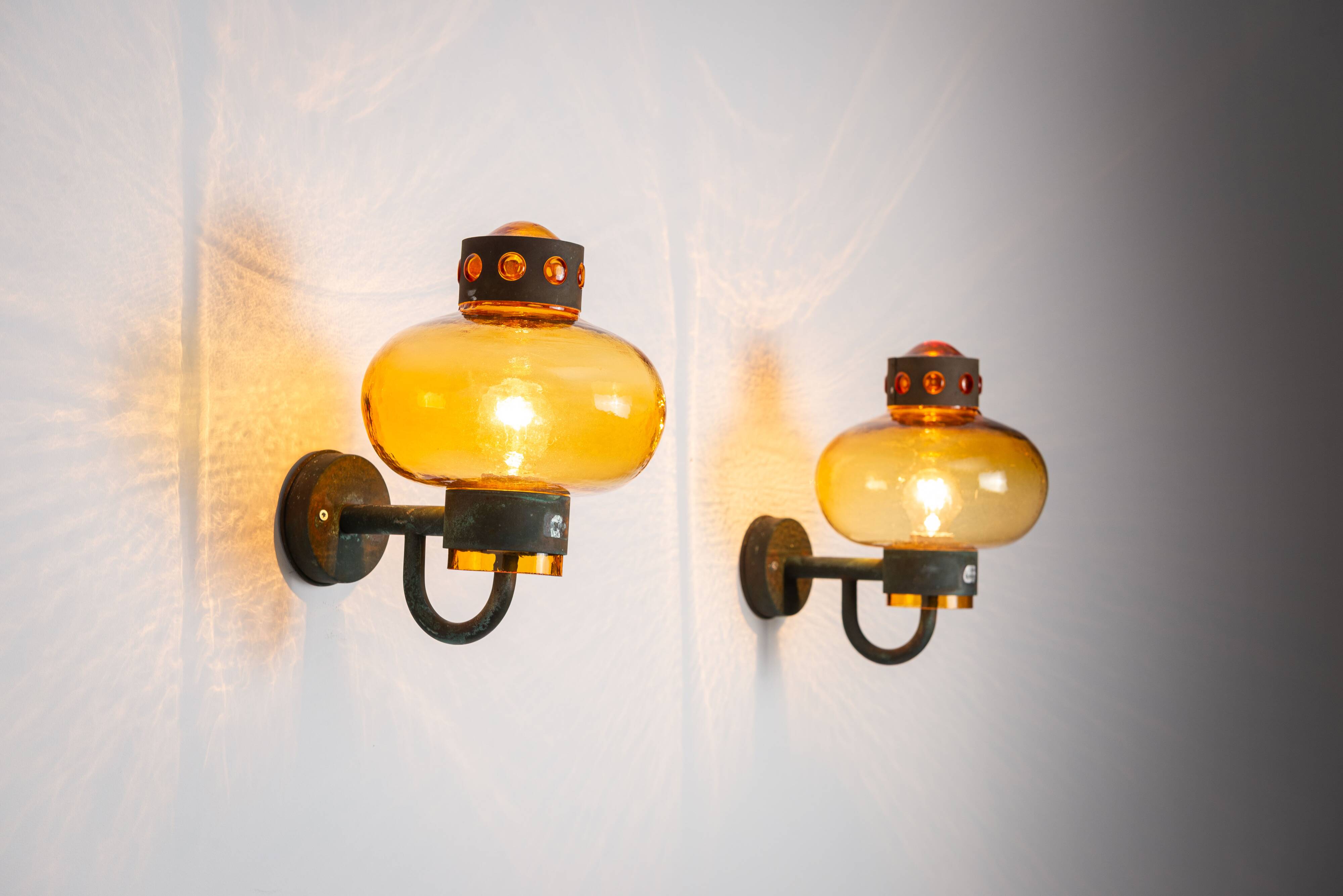 Pair of brass wall lamps with decorated amber coloured shades