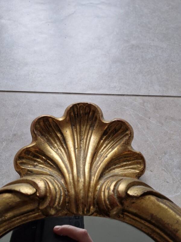 Carved and gilded wooden mirror, the pediment decorated with a shell.