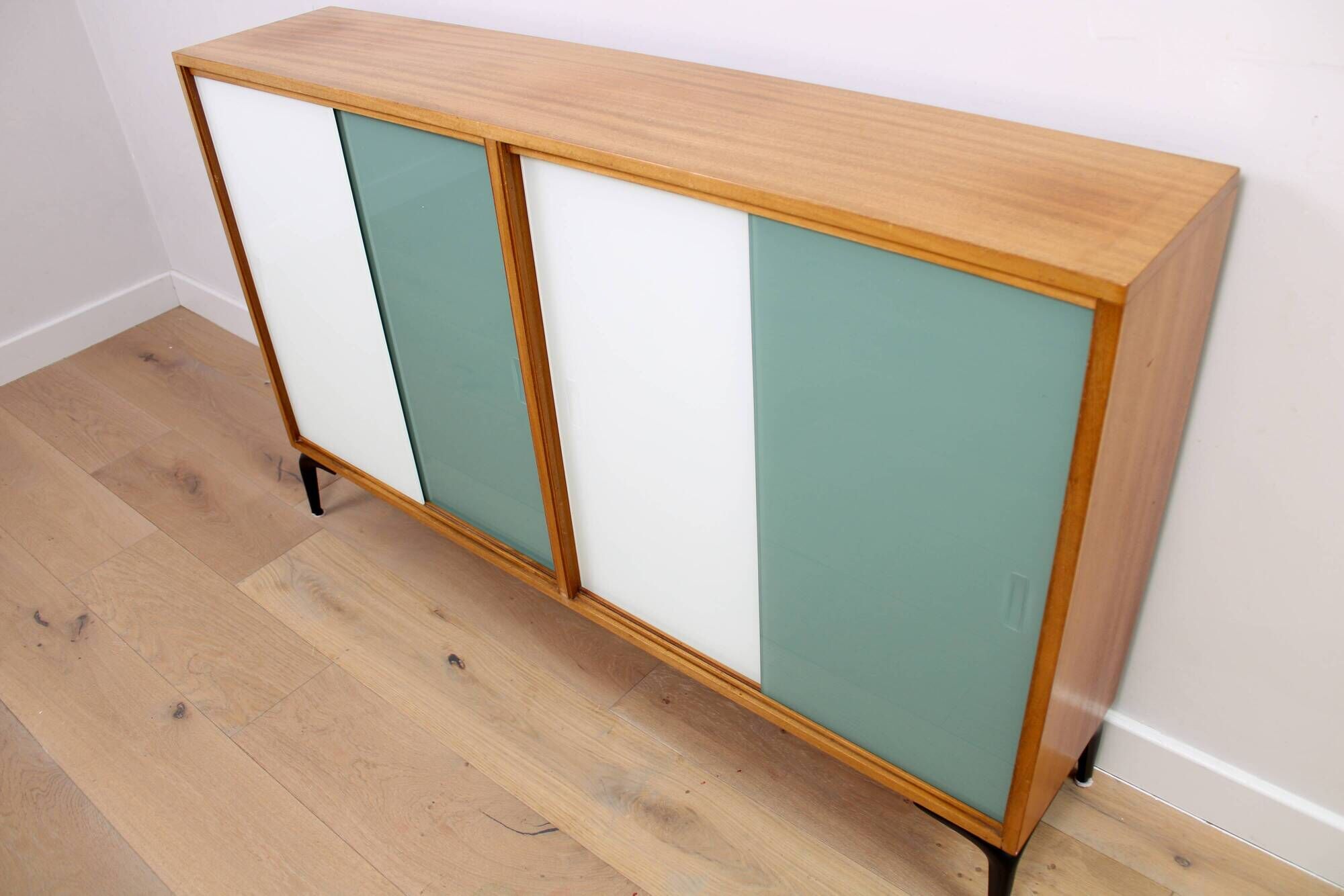 A vintage mid-century bookshelf/sideboard with green and white sliding door