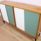 A vintage mid-century bookshelf/sideboard with green and white sliding door