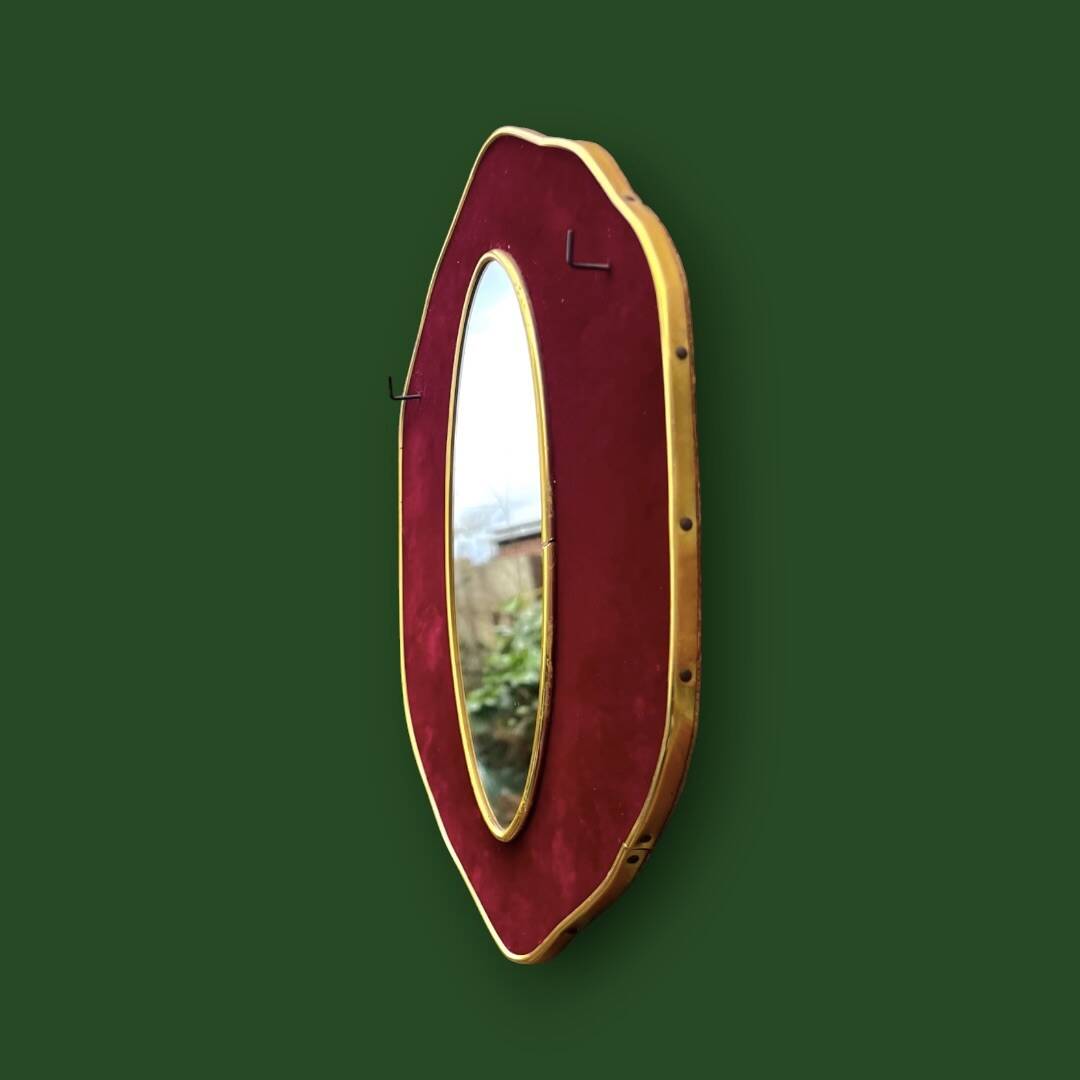 Oval wall mirror in burgundy velvet and brass – 1950s–1960s