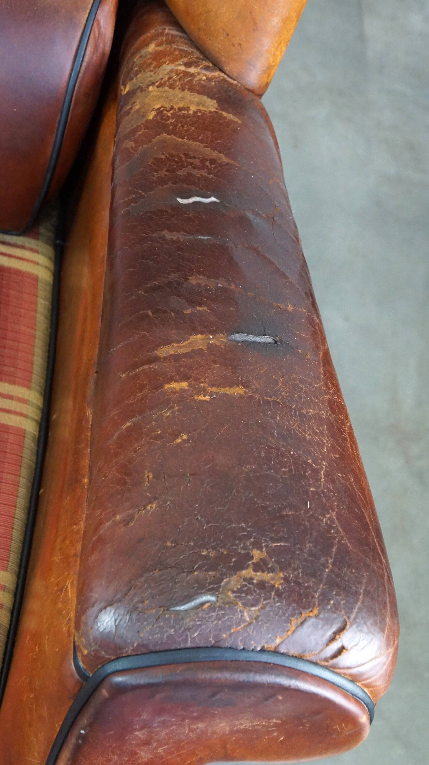 Very large worn sheepskin wing chair with a checked seat cushion
