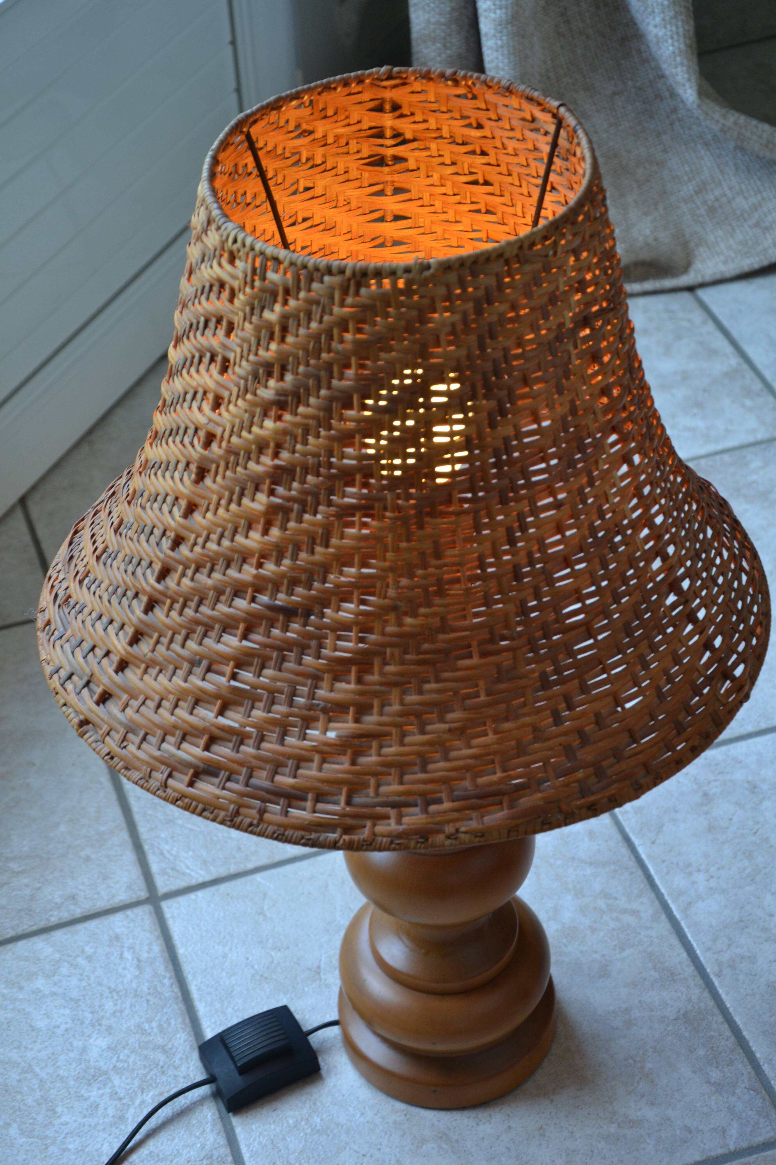 Large wooden lamp with a woven rattan shade.