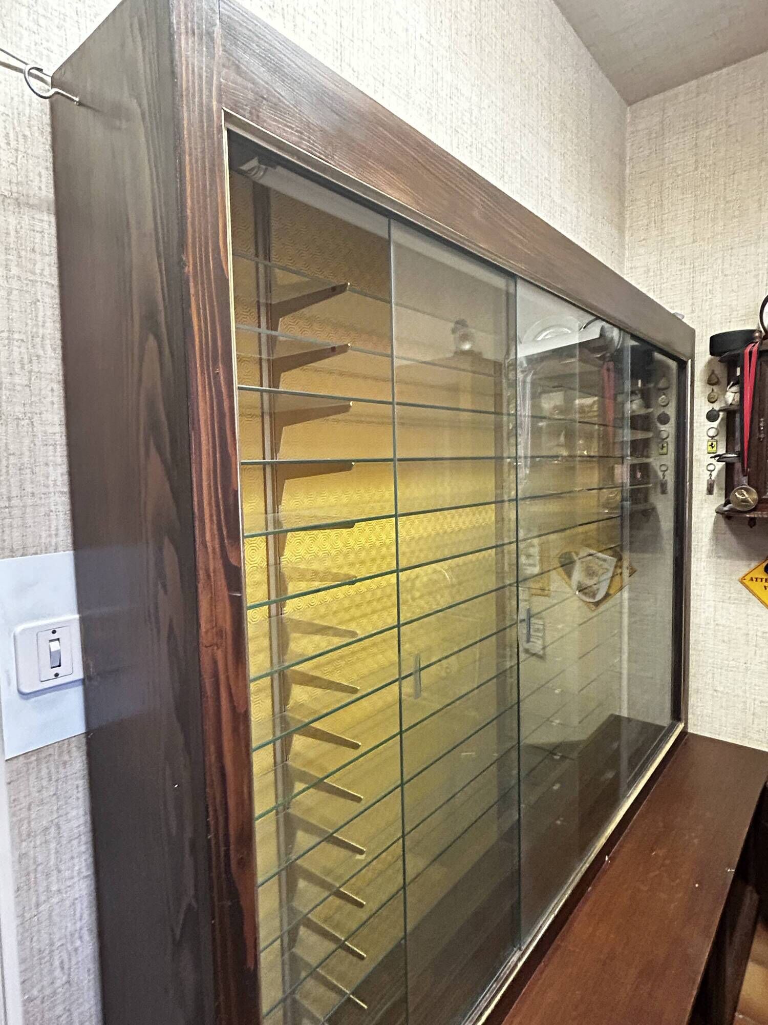 Vintage wooden and glass display cabinet, 15 shelves, gold background.