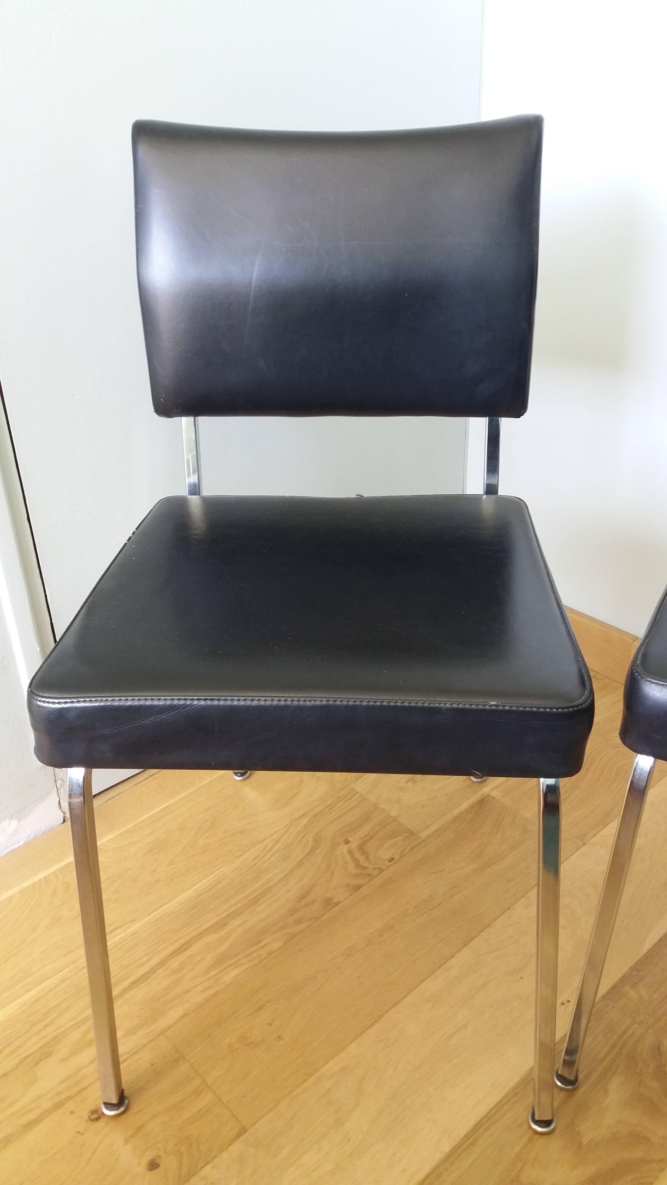 Chrome metal chairs and black faux leather upholstery in retro modernist style.