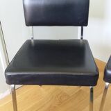 Chrome metal chairs and black faux leather upholstery in retro modernist style.