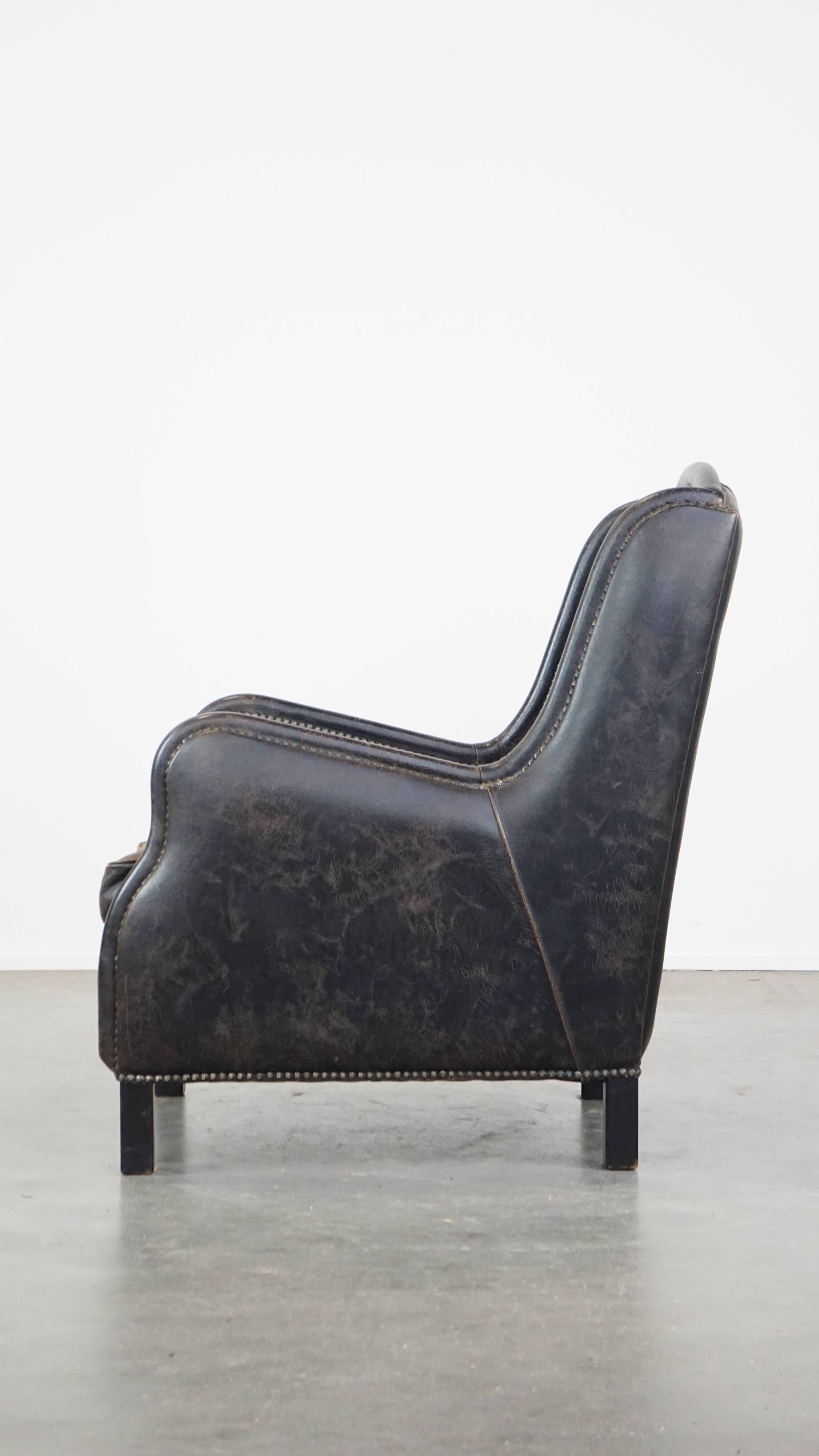 Black cow leather armchair finished with decorative nails, industrial style