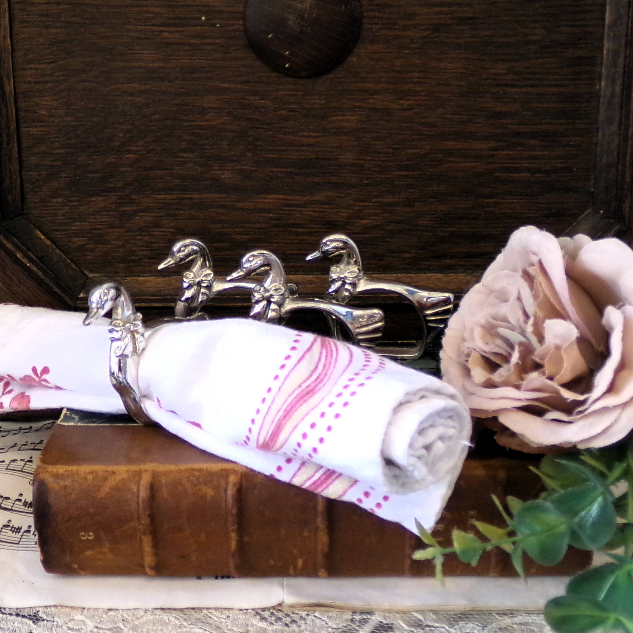Four silver-plated napkin rings in the shape of a duck/goose