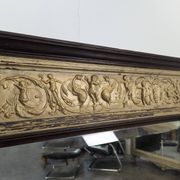 Renaissance-style mirror in wood and copper with a craftsmanship theme.