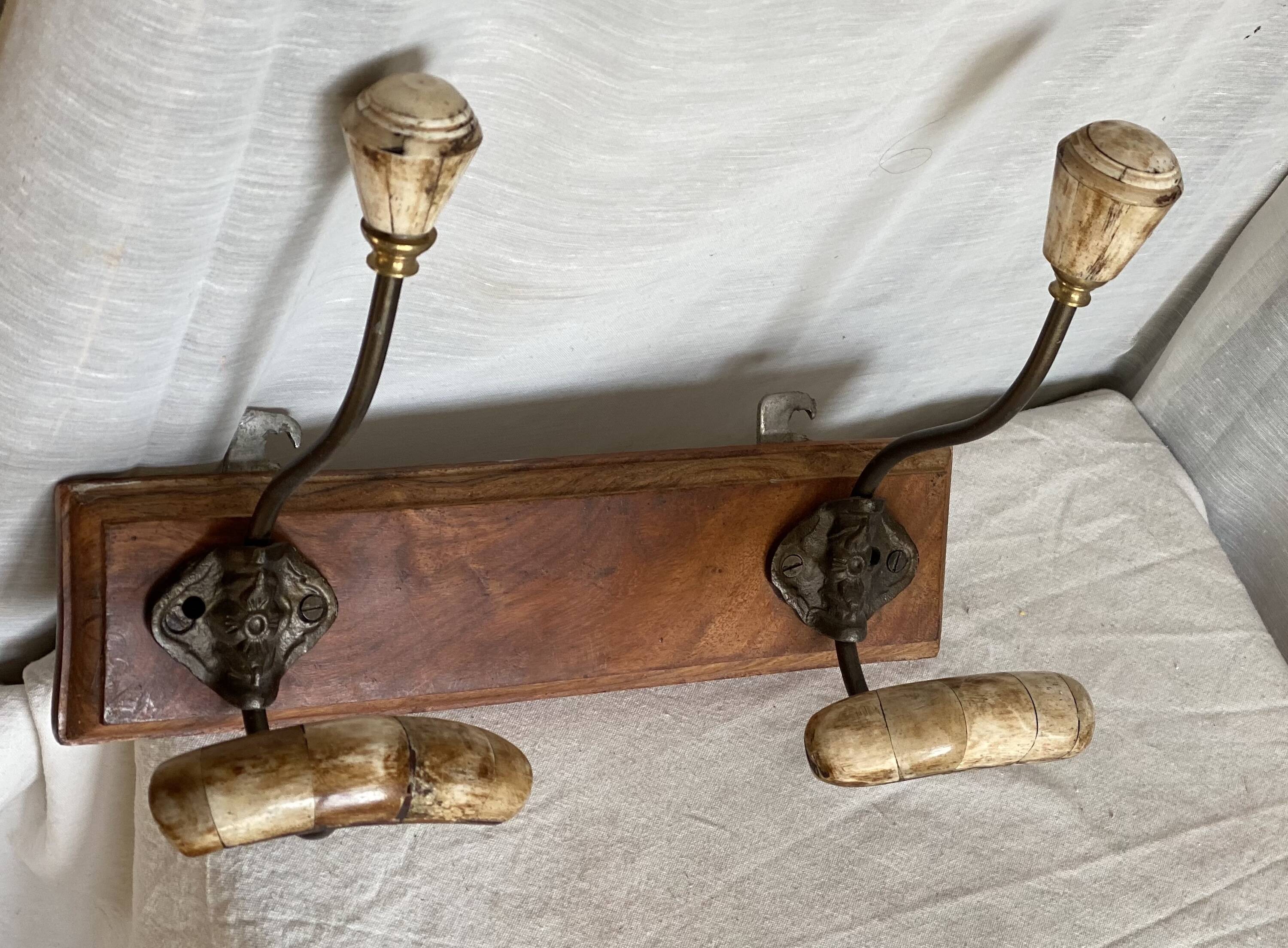 19th-century wall coat rack with 2 metal and horn hooks.
