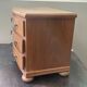 Blonde wooden doll's chest with brass handles.