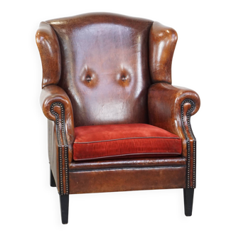 Fauteuil à oreilles en cuir de mouton avec coussin d'assise en velours côtelé rouge et patine