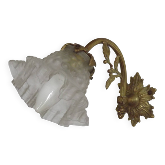 Simple wall sconce in French Art Nouveau bronze with a white glass shade featuring patterns.