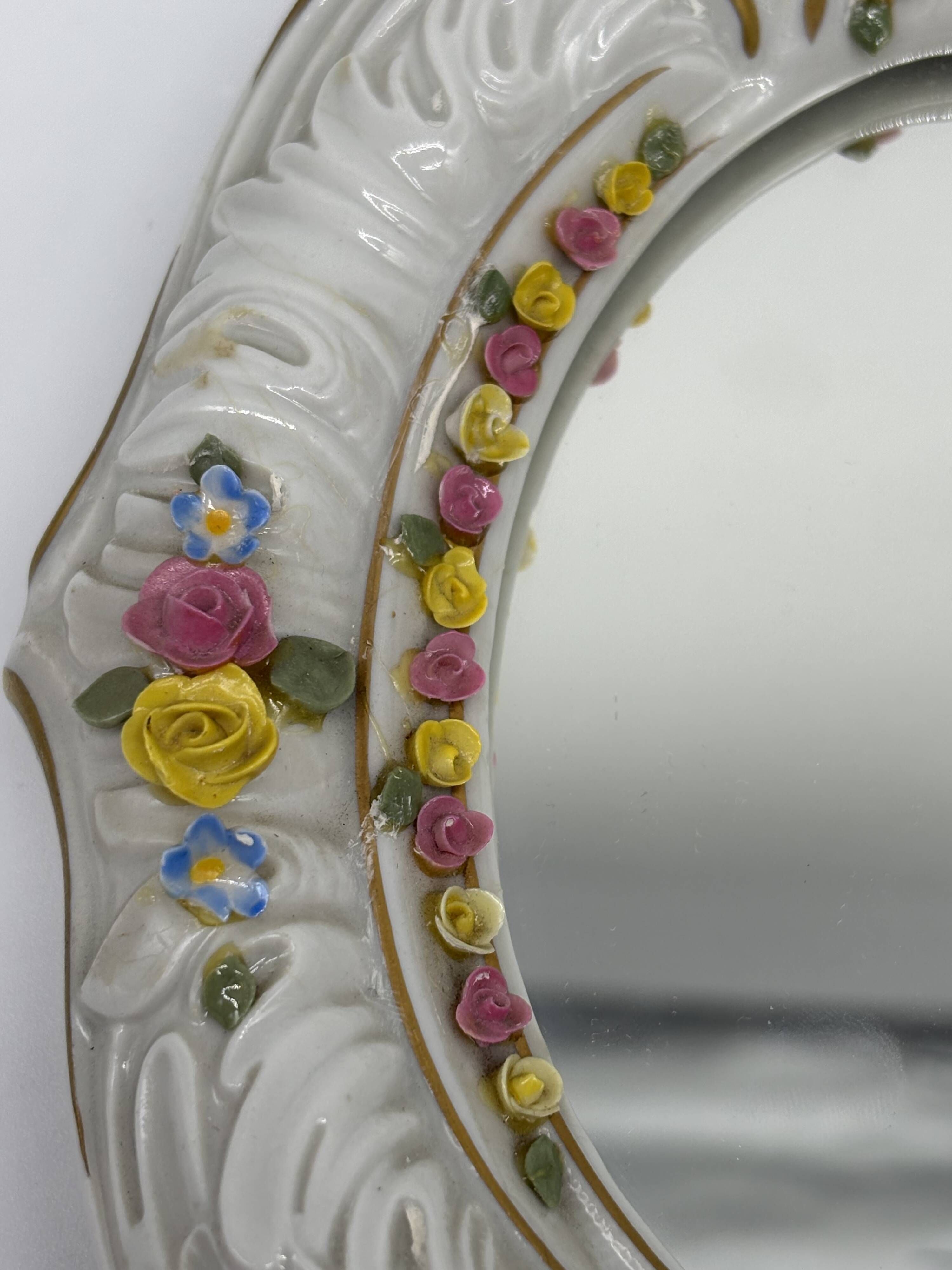 Antique porcelain mirror from Dresden with relief flowers and rococo decoration.