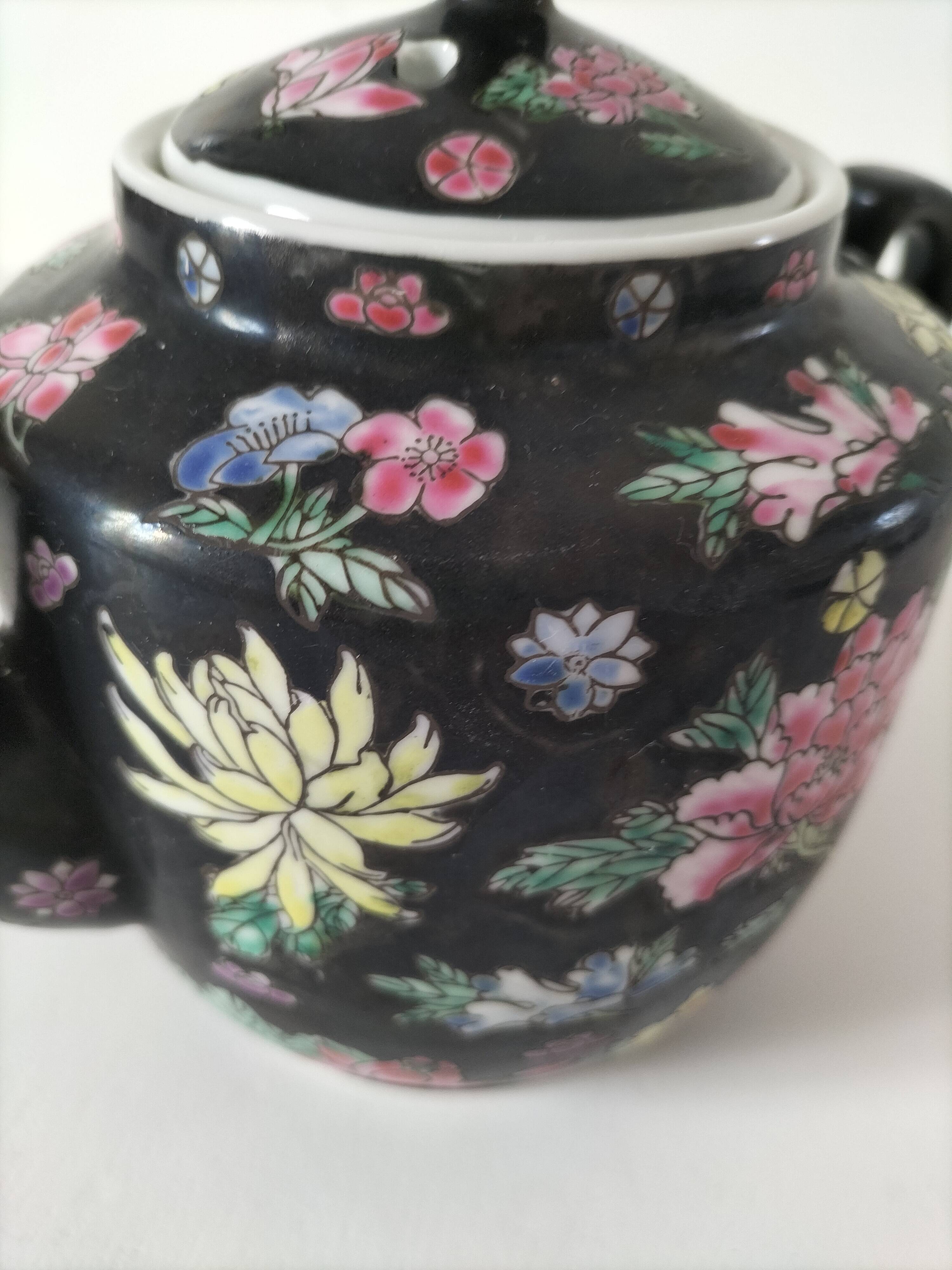 Vintage Chinese teapot with floral polychrome decoration on a black background.