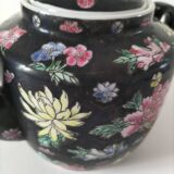 Vintage Chinese teapot with floral polychrome decoration on a black background.