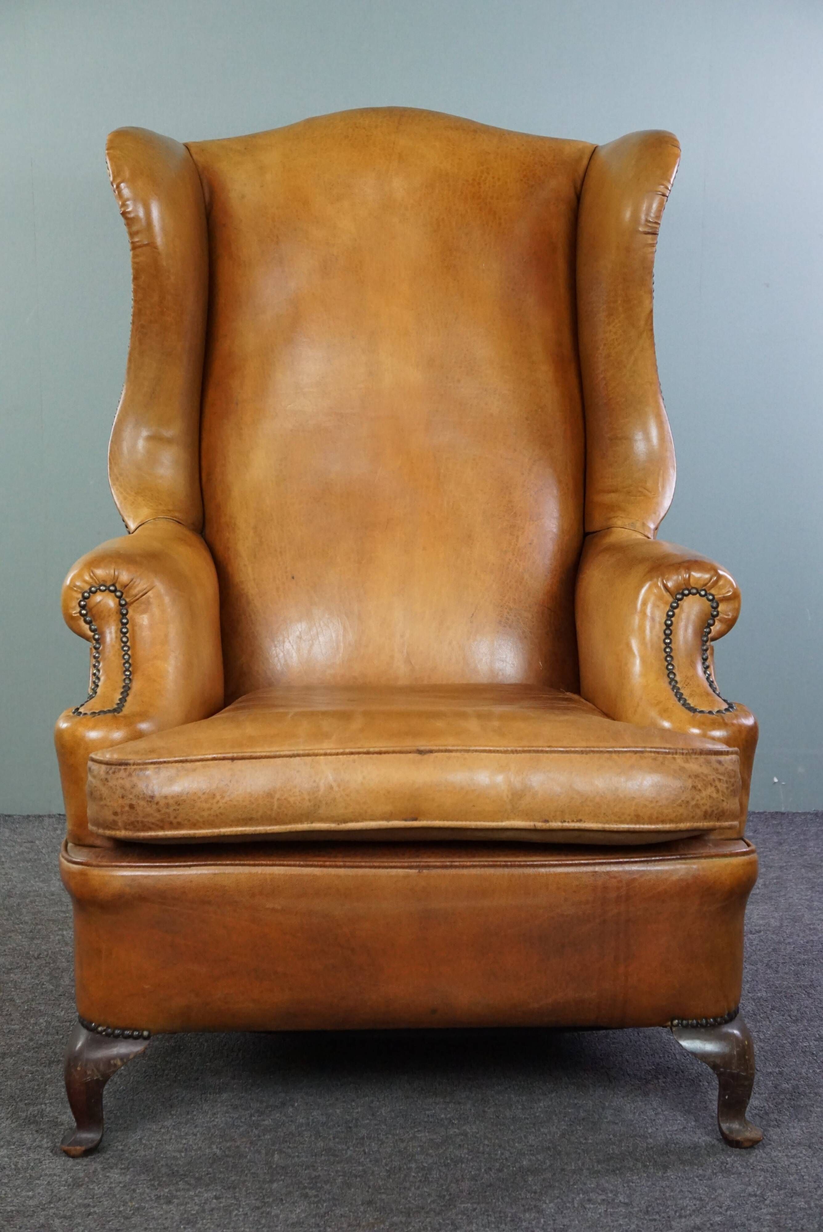 Old wingback armchair made of sheep leather in a correct condition