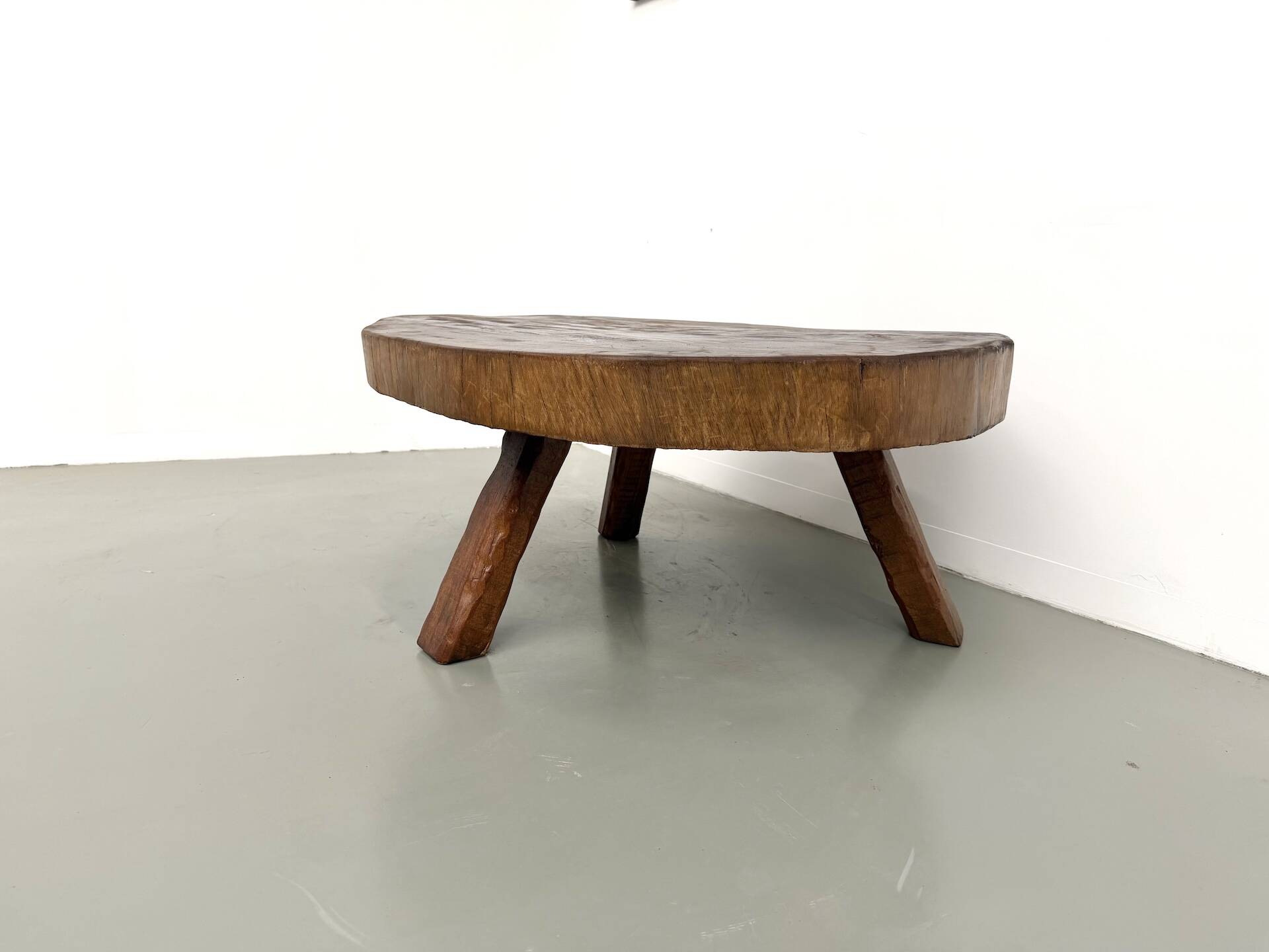 Brutalist coffee table in solid teak, monolithic slab, tripod base.
