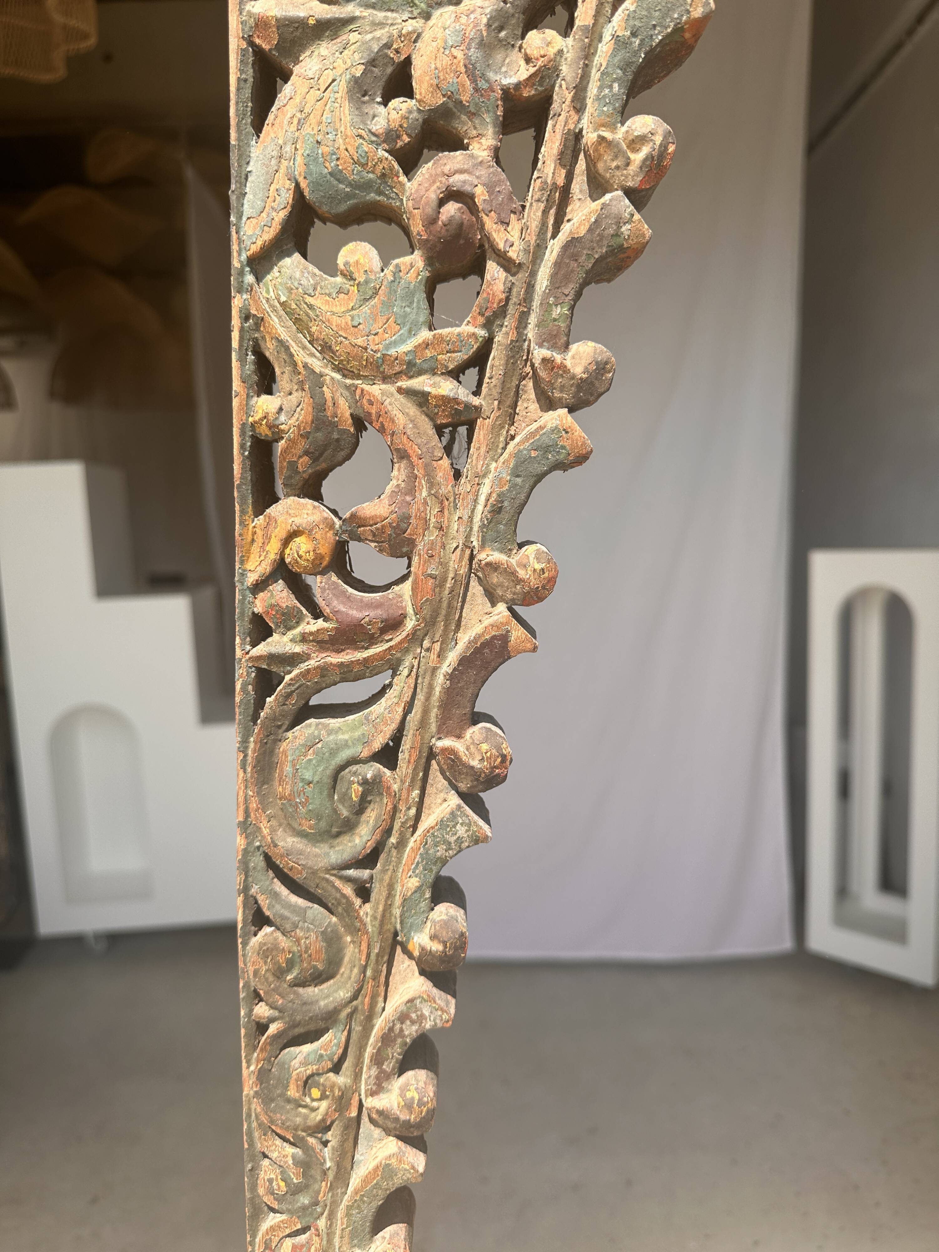 Indonesian construction element in carved wood with intertwined plant motifs mounted on a base (fri