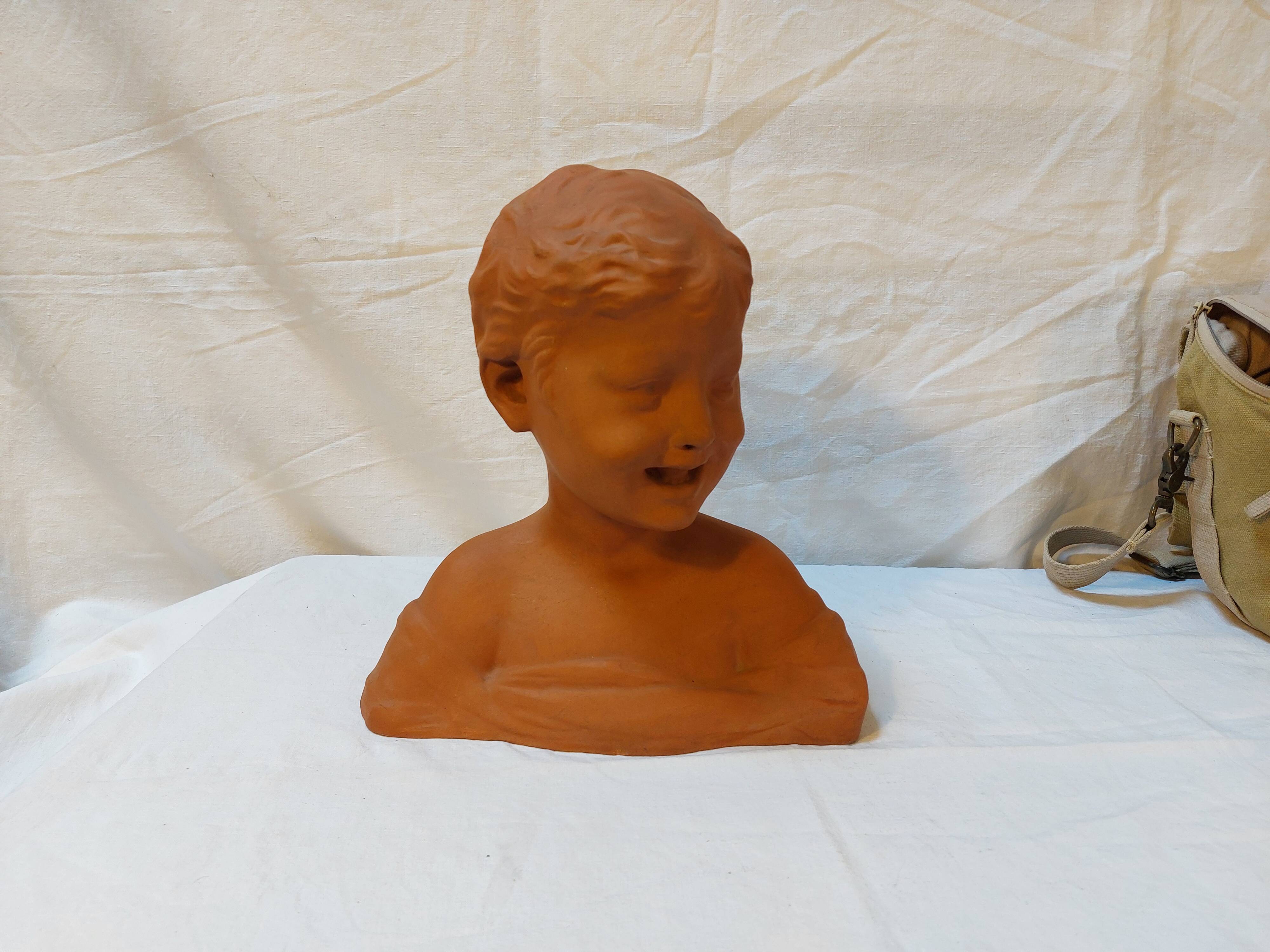 Terracotta bust of a smiling little boy.