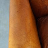 Subtle sheepskin wing chair in good condition on brass front wheels