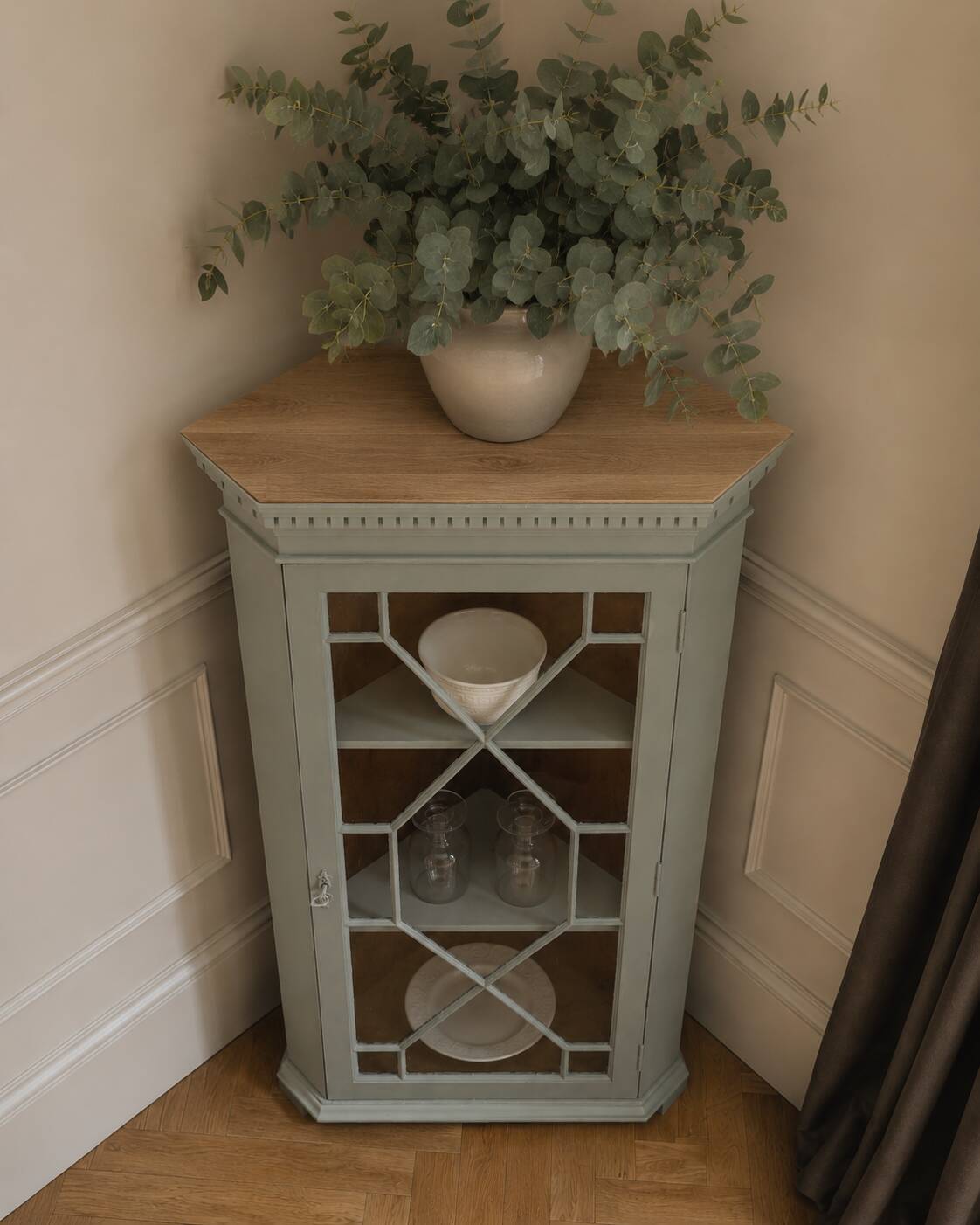 Vintage English corner display cabinet enhanced in grey-green with a wooden top.