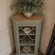 Vintage English corner display cabinet enhanced in grey-green with a wooden top.